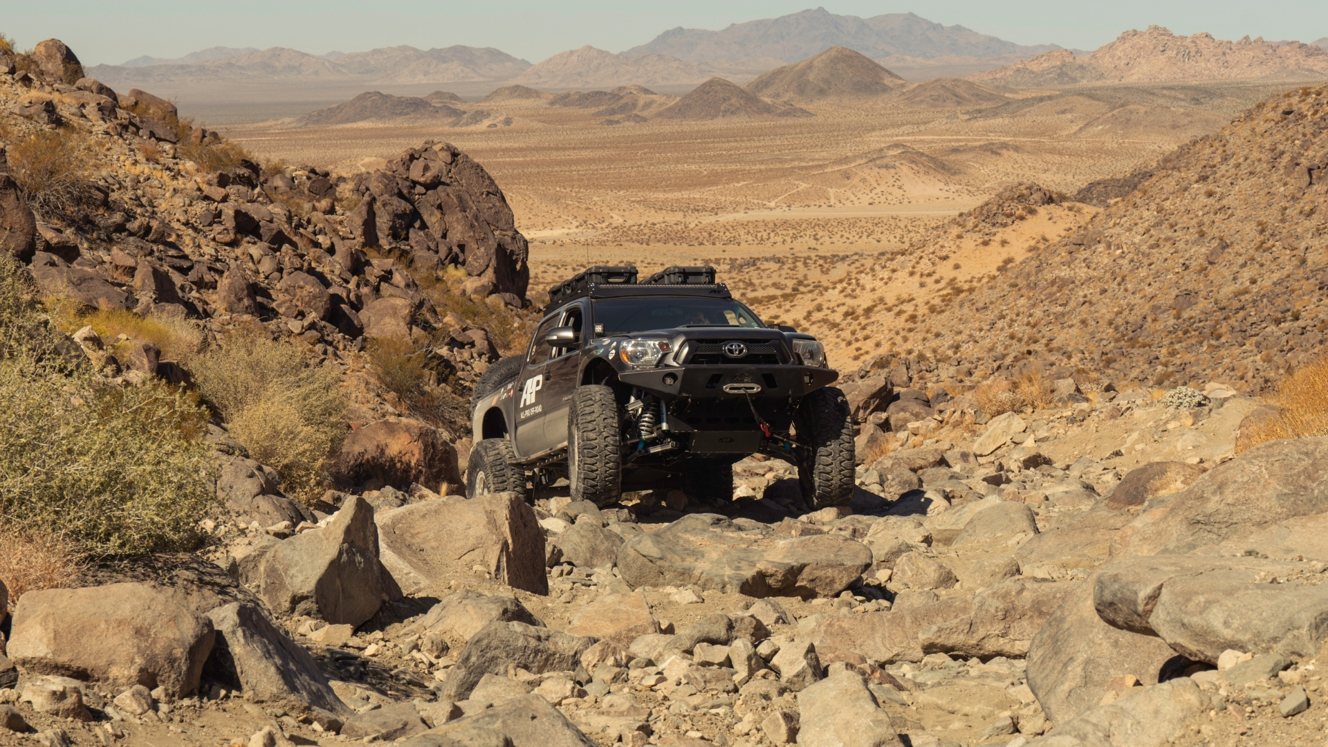 A 4x4 truck crawling over large rocks on an off-road trail